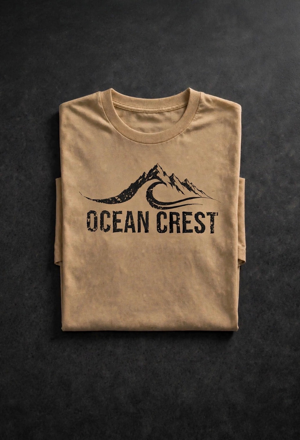 Folded tan t-shirt with black distressed OCEAN CREST graphic.