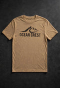 Tan crewneck t-shirt with black mountain-and-wave OCEAN CREST graphic.