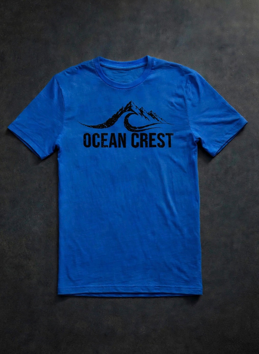 Bright blue t-shirt with black mountain-and-wave OCEAN CREST graphic.